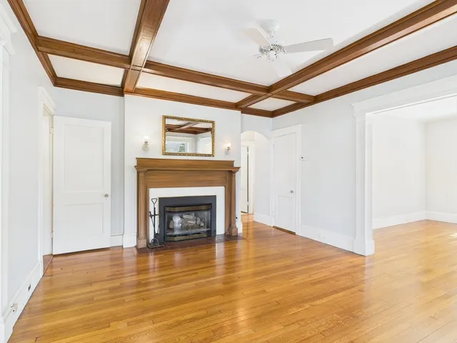 a view of an empty room with wooden floor fireplace and a window