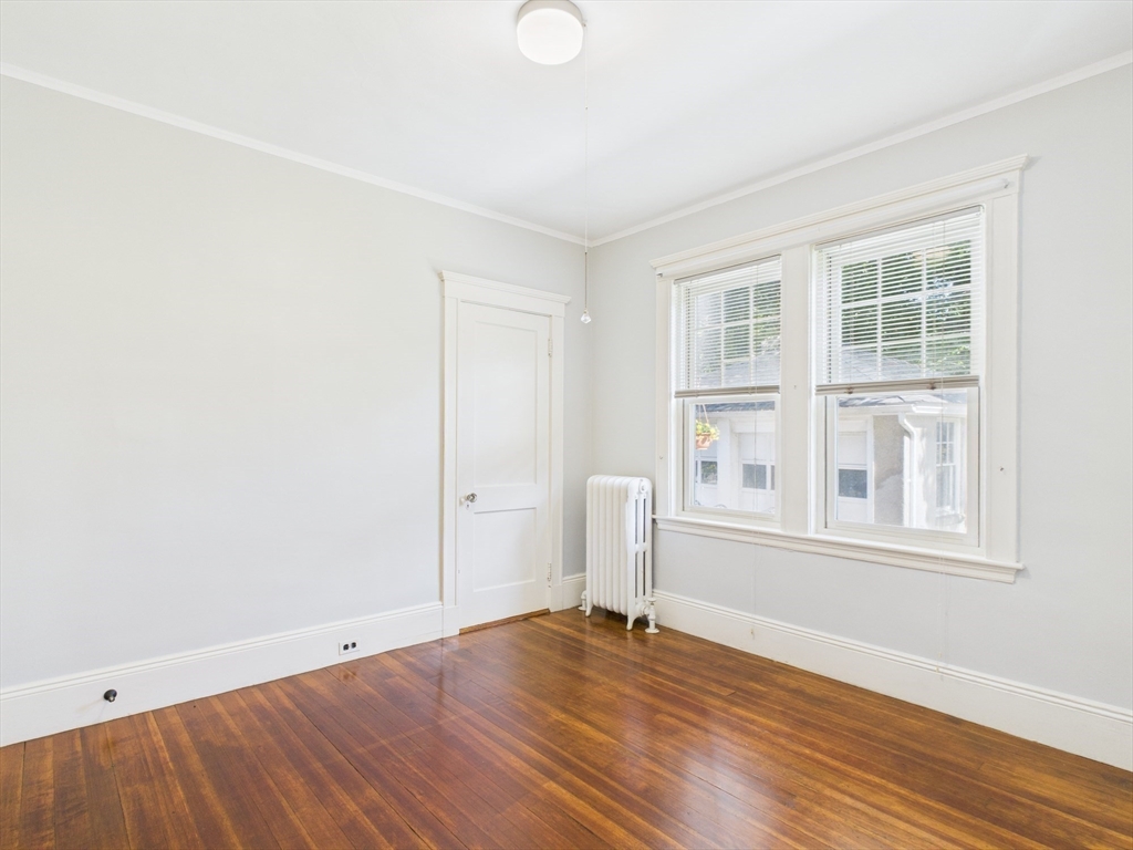 1120 Centre Street, Unit 1 Newton, MA 02459 - Photo 26 of 34 an empty room with wooden floor and windows