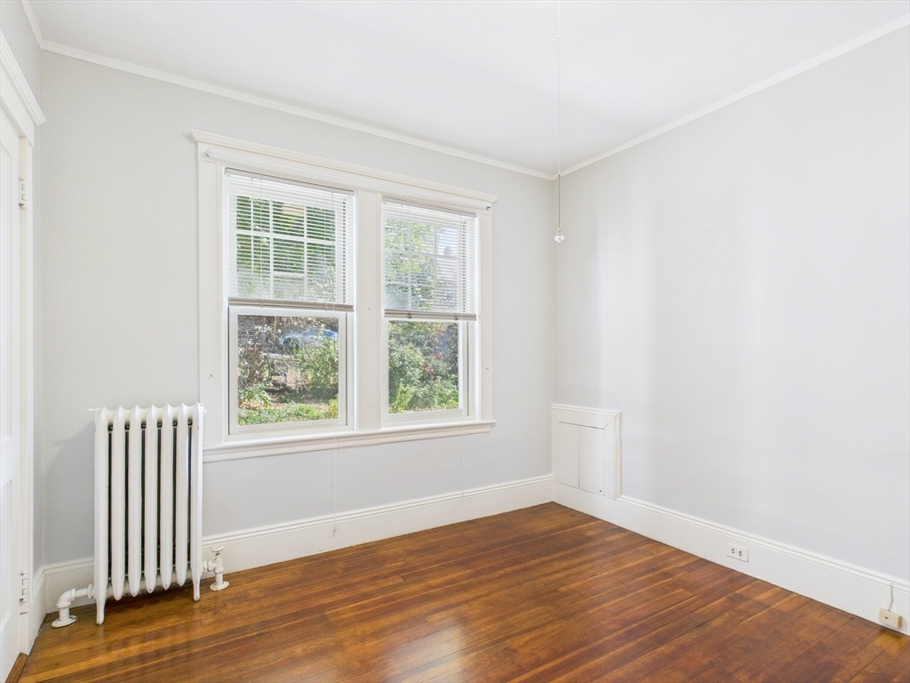 1120 Centre Street, Unit 1 Newton, MA 02459 - Photo 27 of 34 an empty room with wooden floor and windows