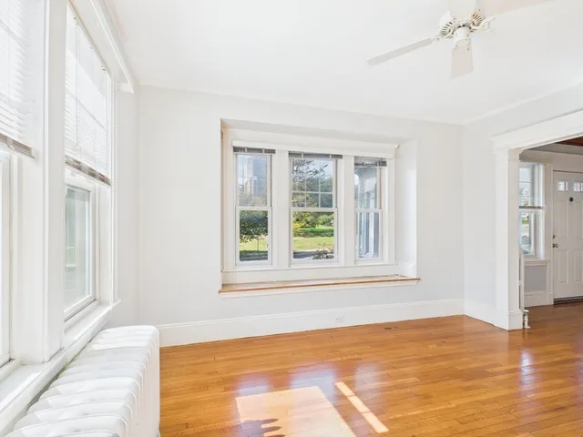 a view of an empty room with window and wooden floor