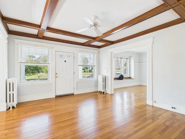 a view of an empty room with a window and wooden floor