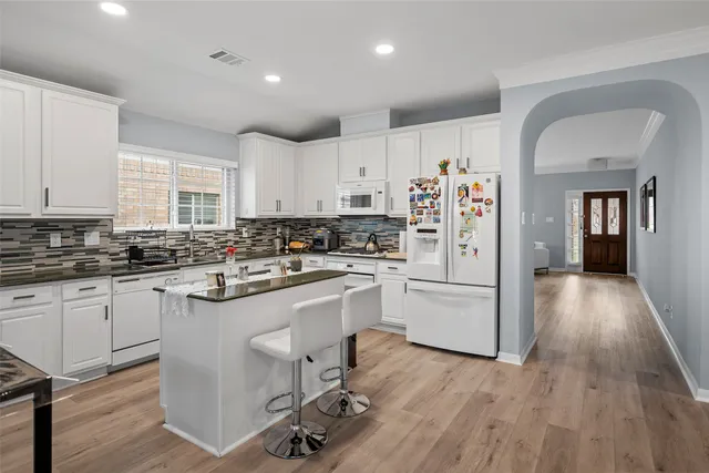 a kitchen with a refrigerator a white cabinets and wooden floor