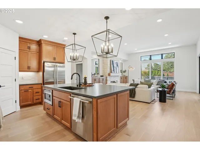 a kitchen with stainless steel appliances granite countertop a sink dishwasher a stove and a dining table with wooden floor