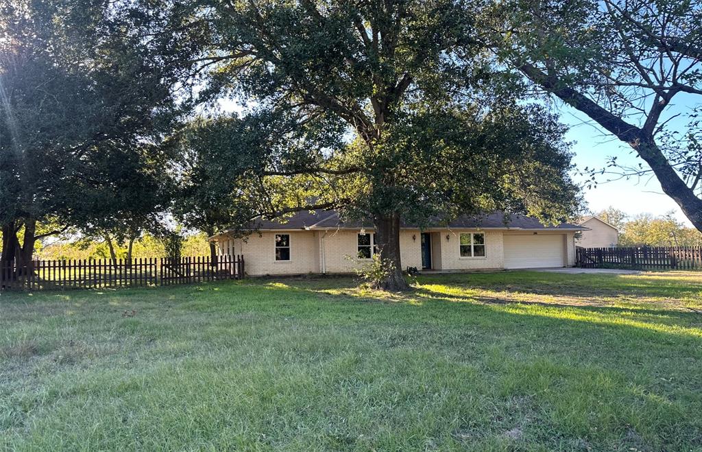 a view of a house with a yard and large trees