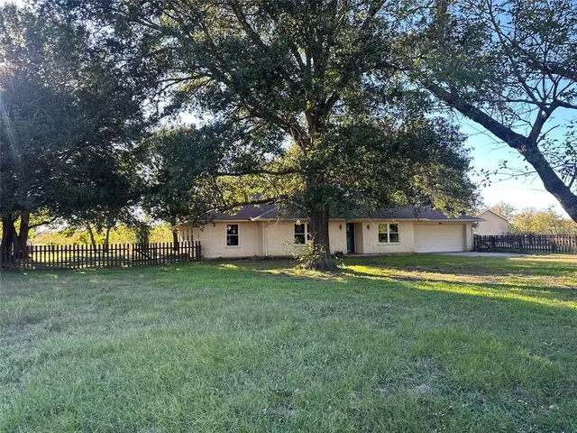 a view of a house with a big yard and large trees