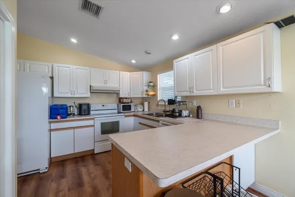 a kitchen with kitchen island a stove a sink a refrigerator and cabinets