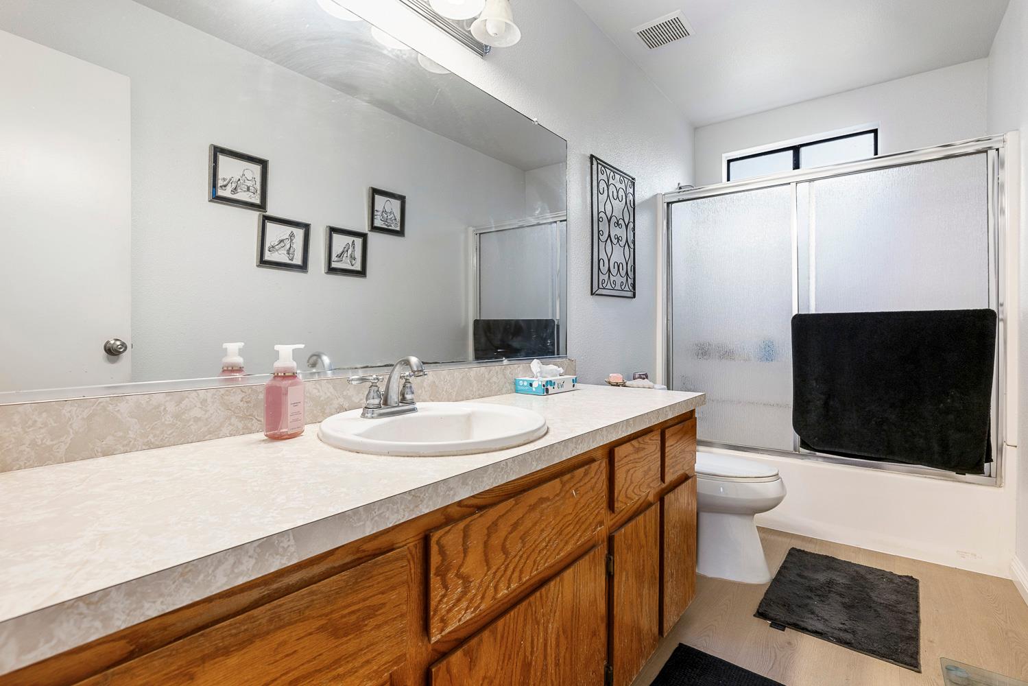 1592 North Ferger Avenue Fresno, CA 93728 - Photo 21 of 30 a bathroom with a sink a toilet a shower and a mirror