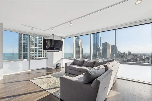 a living room with furniture floor to ceiling window and a flat screen tv