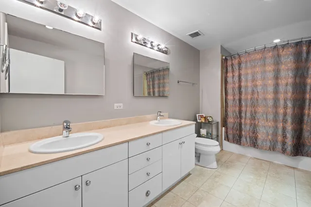 a bathroom with a double vanity sink a toilet and a mirror