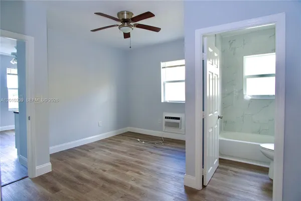 a view of empty room with wooden floor and fan