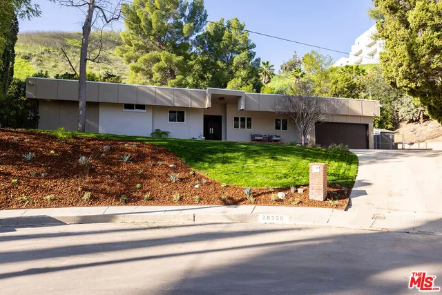 a view of a house with a yard and a large tree
