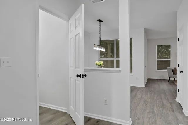 a view of a hallway with wooden floor and a room