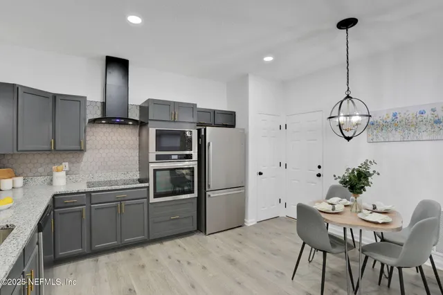 a kitchen with stainless steel appliances kitchen island granite countertop a dining table chairs sink and microwave
