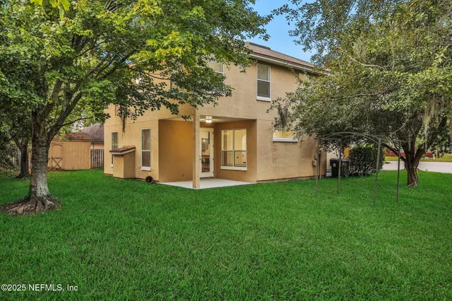 a view of a white house with a big yard and large tree