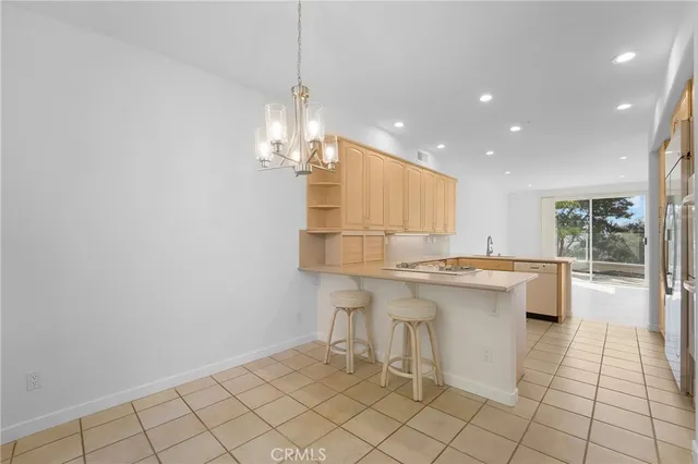 a large white kitchen with a sink and chandelier