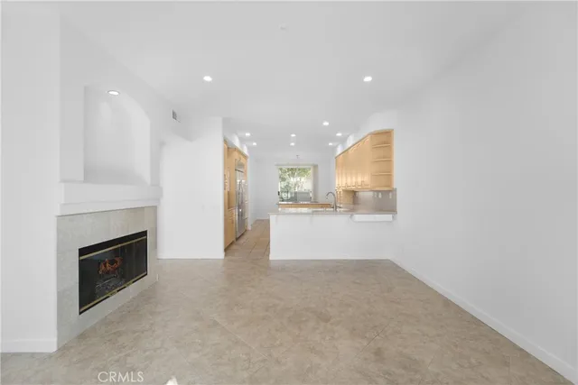 an empty room with kitchen and fireplace