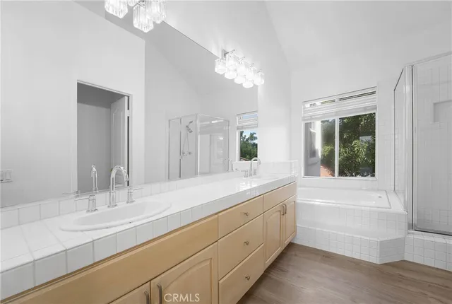 a bathroom with a granite countertop sink a large mirror a bathtub and next to a window
