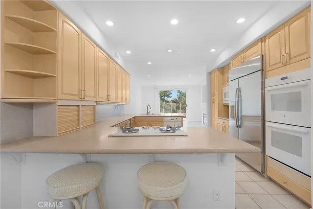 a kitchen with stainless steel appliances granite countertop a sink a stove a refrigerator a cabinets and wooden floor