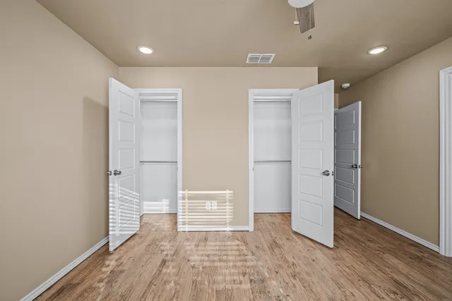 a view of an empty room with wooden floor and closet