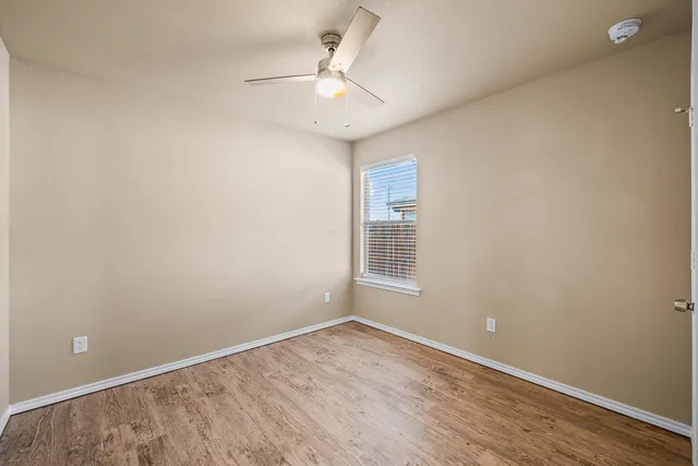 an empty room with a chandelier fan and windows