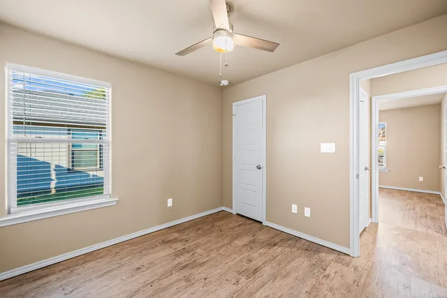a view of an empty room with window and wooden floor