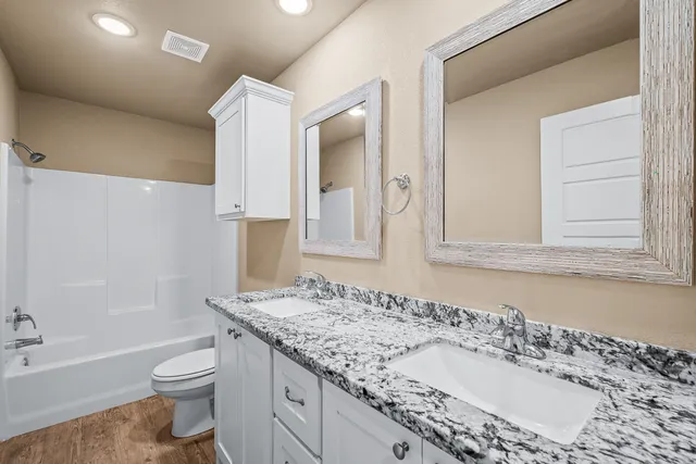 a bathroom with a granite countertop sink a toilet and a bathtub