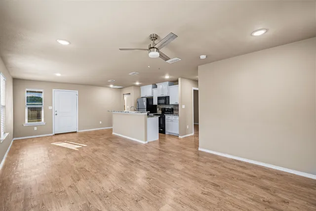a view of a kitchen with kitchen island wooden floor appliances and a window