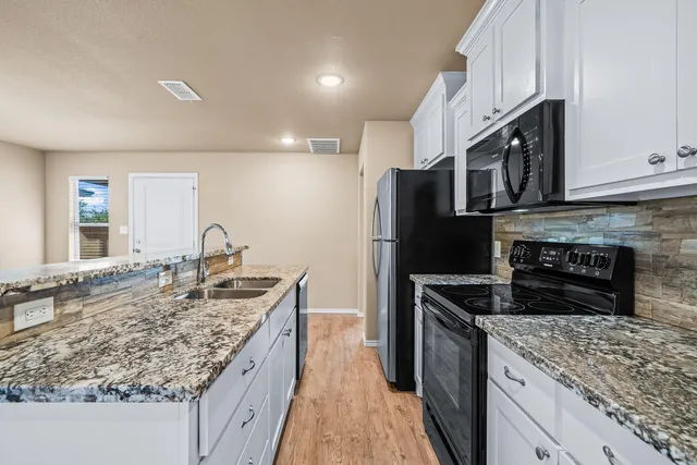 a kitchen with stainless steel appliances granite countertop a sink stove and refrigerator