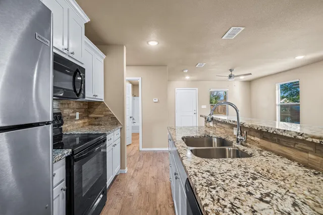 a kitchen with granite countertop a sink stove and refrigerator