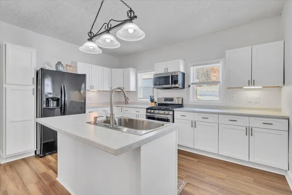 a kitchen with stainless steel appliances granite countertop a stove a sink dishwasher and a refrigerator with wooden floor