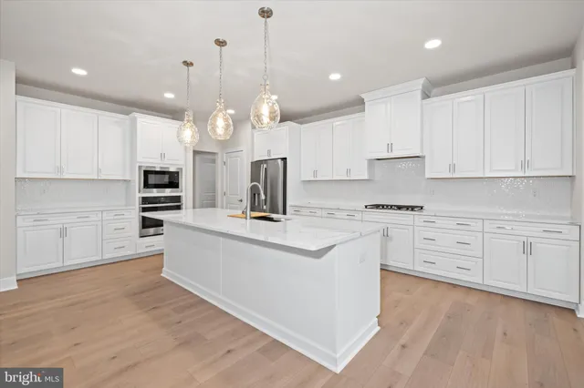a kitchen with stainless steel appliances white cabinets and wooden floors