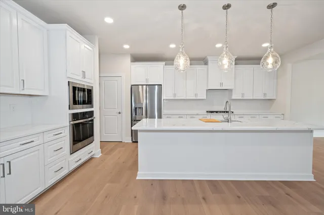 a large kitchen with kitchen island a stove a sink a refrigerator and a wooden floor