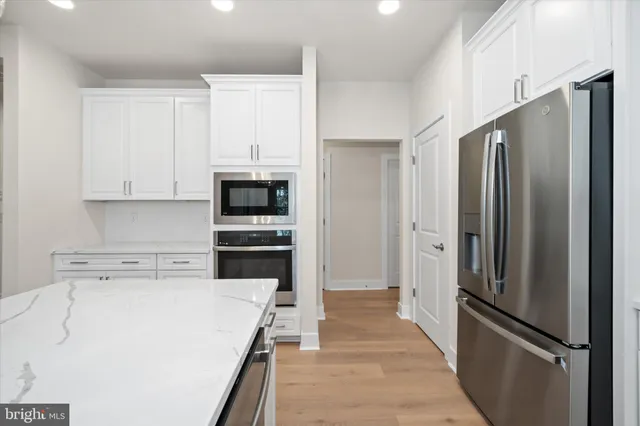 a view of an empty room with wooden floor and a kitchen
