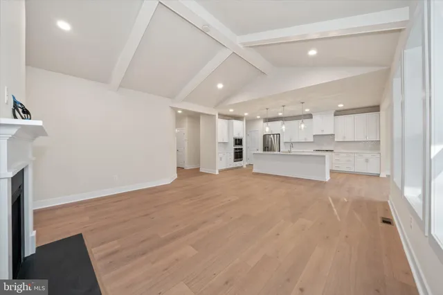 a view of an empty room with wooden floor and windows