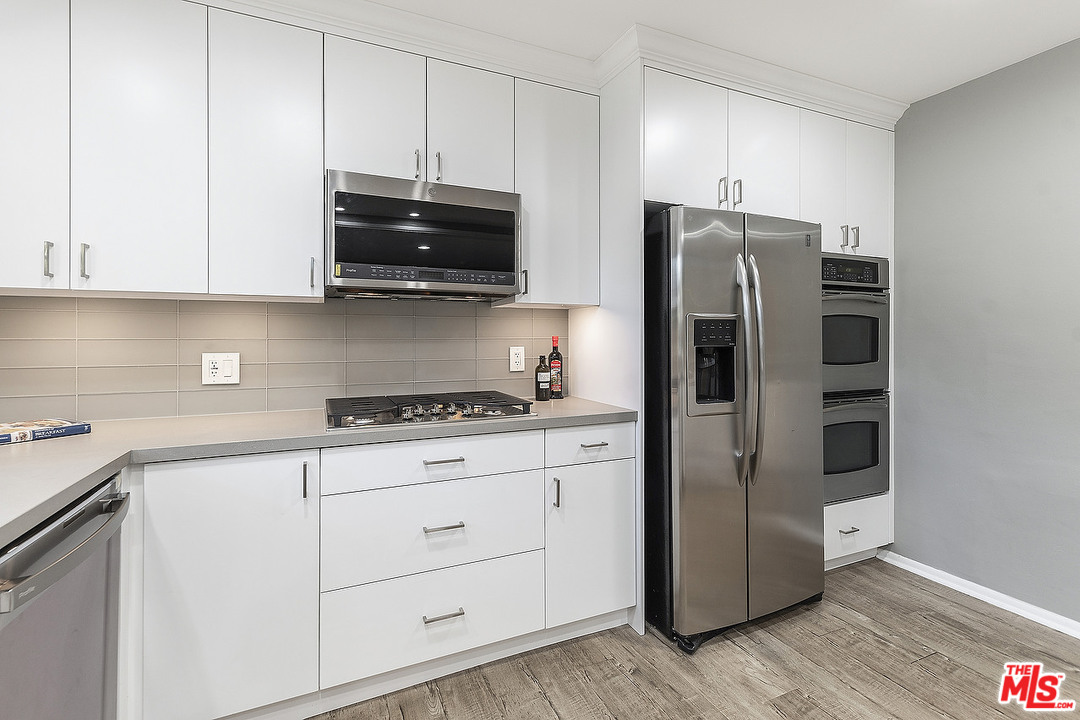 711 Sierra Drive Beverly Hills, CA 90210 - Photo 11 of 40 a kitchen with stainless steel appliances a refrigerator stove and sink
