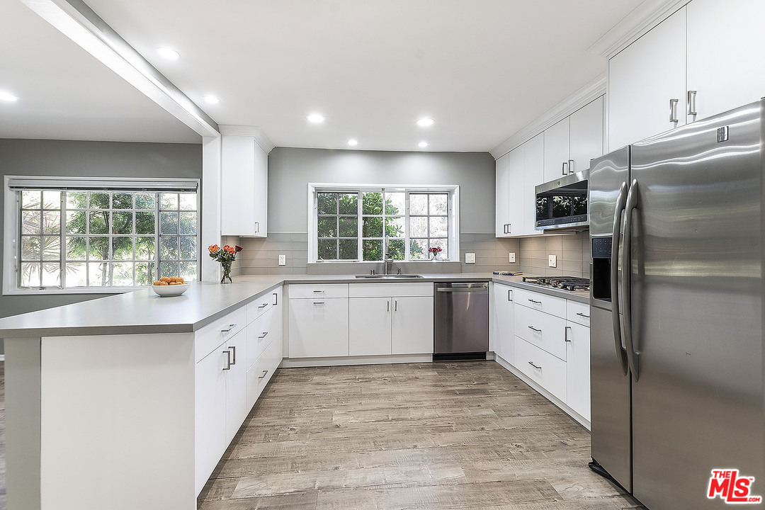 711 Sierra Drive Beverly Hills, CA 90210 - Photo 12 of 40 a large kitchen with granite countertop a large counter top space a sink stainless steel appliances and windows