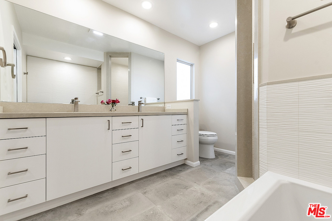 711 Sierra Drive Beverly Hills, CA 90210 - Photo 26 of 40 a spacious bathroom with a double vanity sink a mirror and a toilet