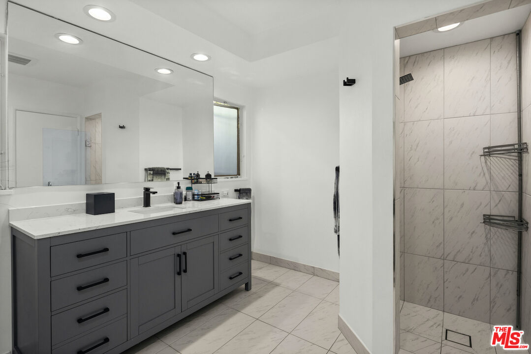 711 Sierra Drive Beverly Hills, CA 90210 - Photo 34 of 40 a bathroom with a double vanity sink a mirror and shower