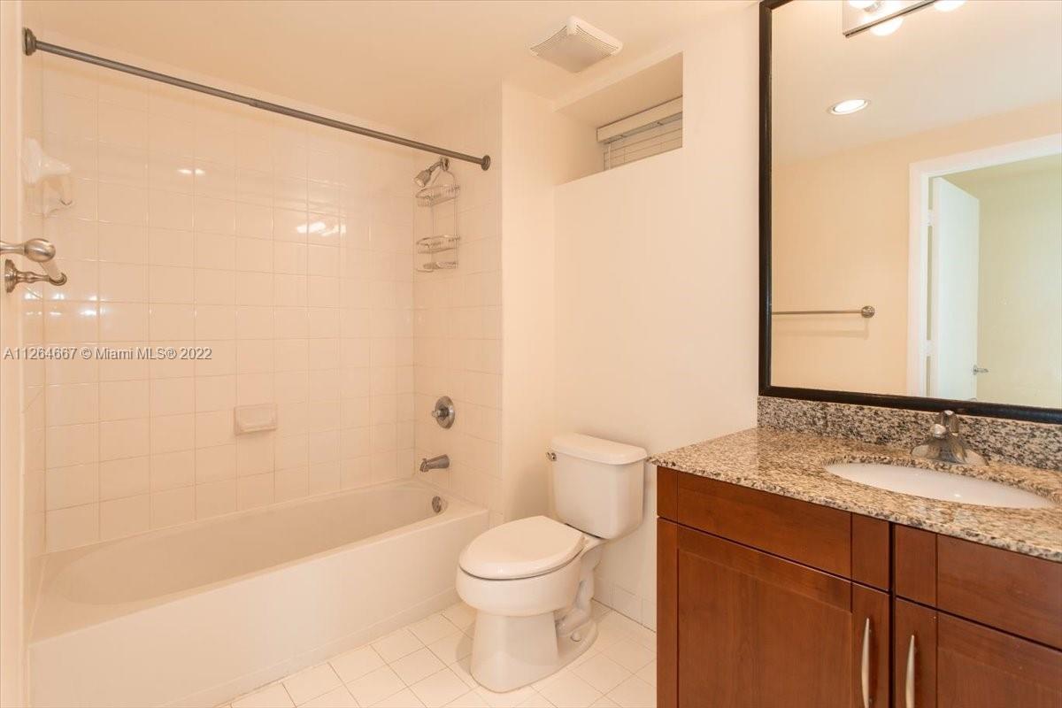 7275 Southwest 90th Street, Unit C310 Miami, FL 33156 - Photo 15 of 40 a bathroom with a granite countertop sink toilet a shower and a mirror