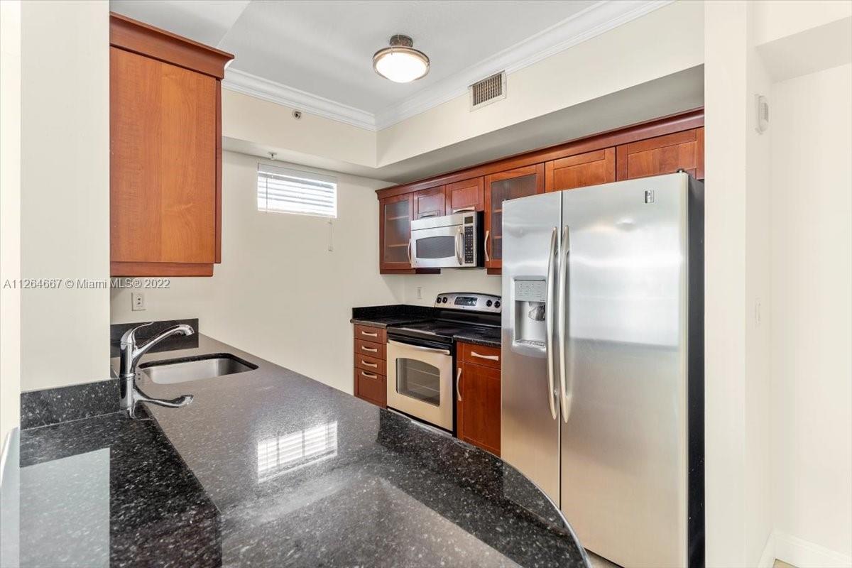 7275 Southwest 90th Street, Unit C310 Miami, FL 33156 - Photo 7 of 40 a kitchen with stainless steel appliances granite countertop a refrigerator a sink and a stove