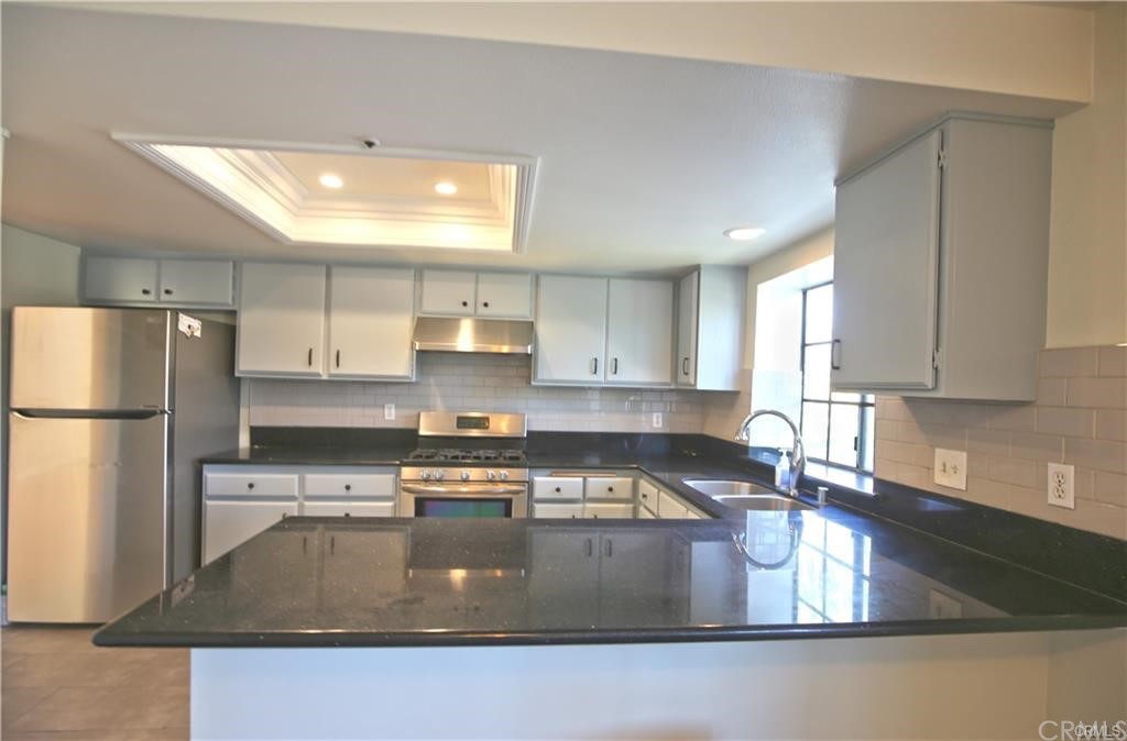 105 East Beacon Street, Unit A Alhambra, CA 91801 - Photo 4 of 15 a kitchen with stainless steel appliances granite countertop a refrigerator a sink a stove and white cabinets