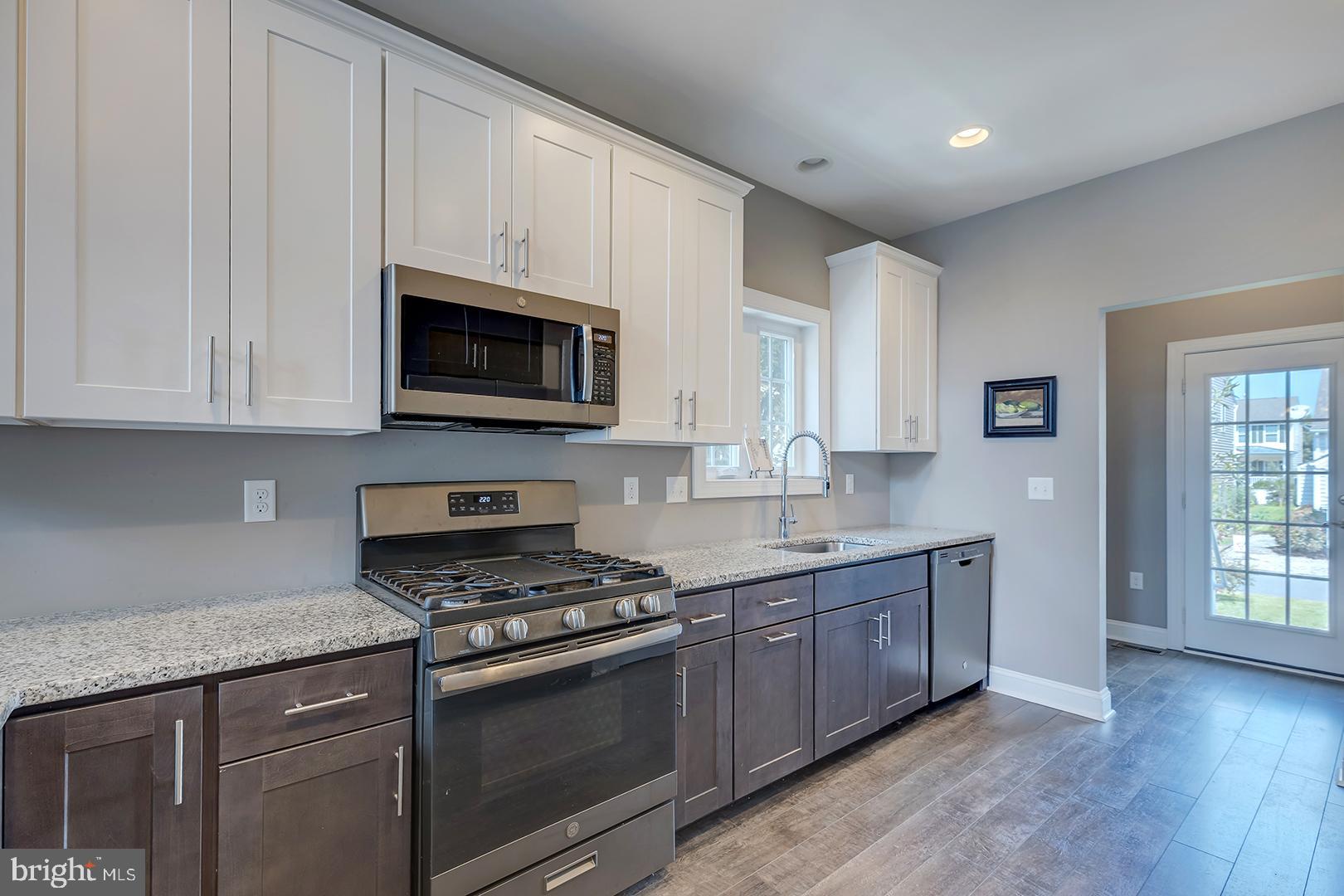303 Brick Lane Milton, DE 19968 - Photo 15 of 71 a kitchen with granite countertop a stove a sink and a microwave