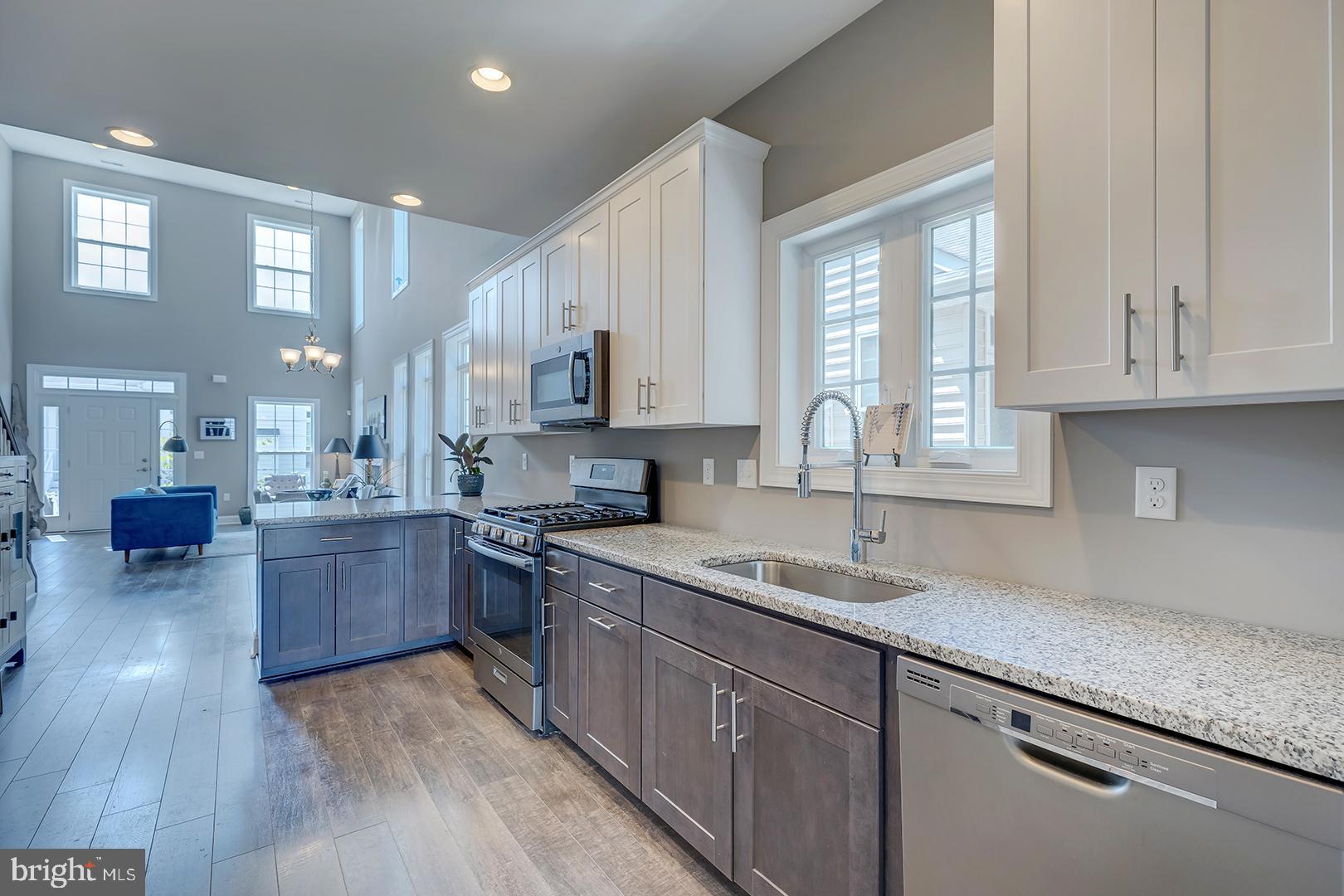 303 Brick Lane Milton, DE 19968 - Photo 16 of 71 a kitchen with kitchen island granite countertop wooden floors wooden cabinets and sink