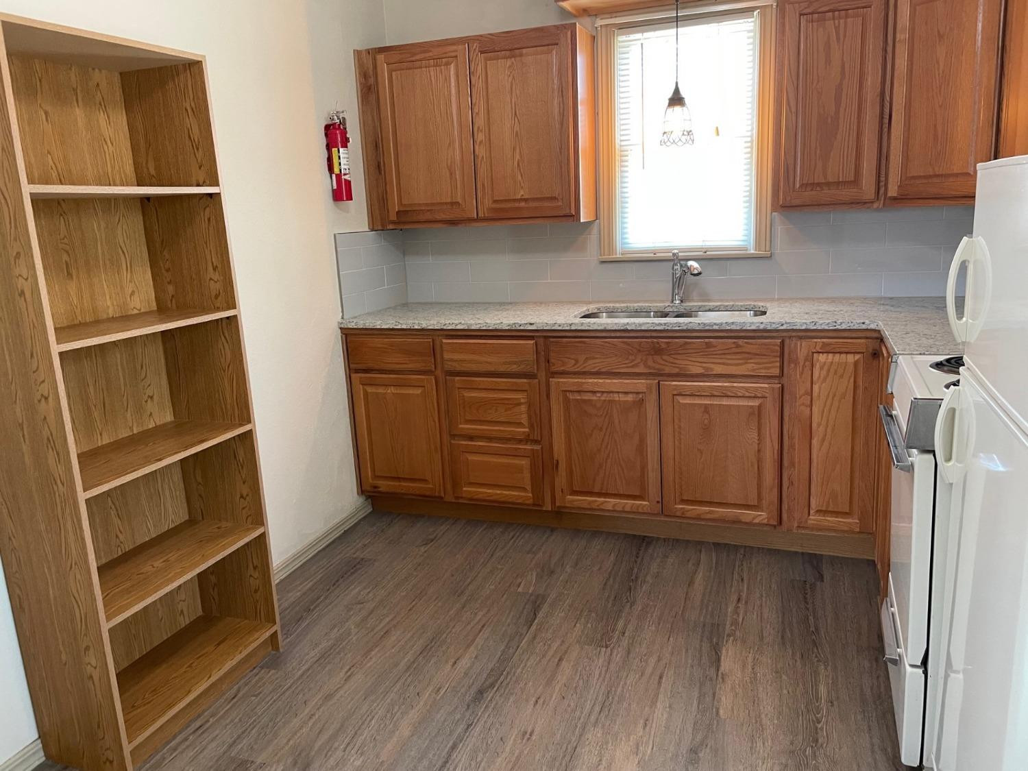3018 29th Street Lubbock, TX 79410 - Photo 11 of 14 a kitchen with granite countertop wooden cabinets a sink and a window