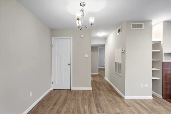 a view of a hallway with wooden floor and a chandelier
