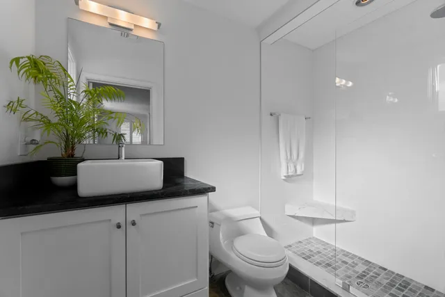 a bathroom with a granite countertop toilet sink and mirror
