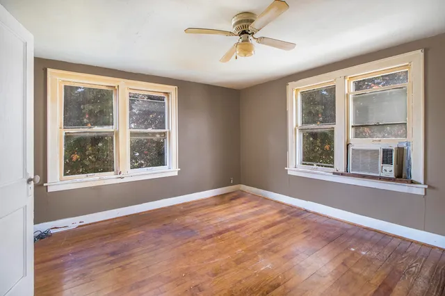 a view of an empty room with a window and wooden floor