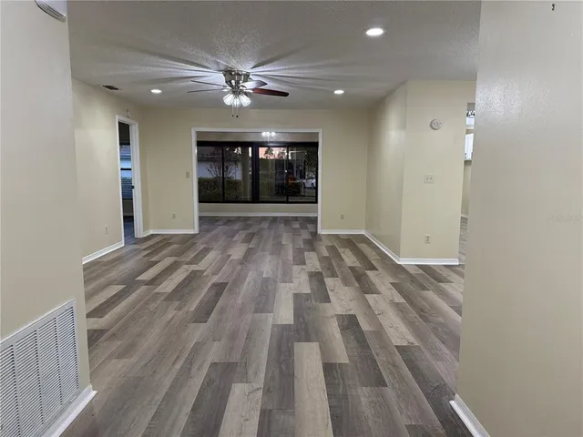 a view of an empty room with wooden floor and chandelier