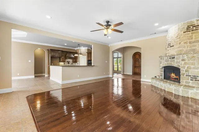 a view of a livingroom with fireplace a ceiling fan and wooden floor