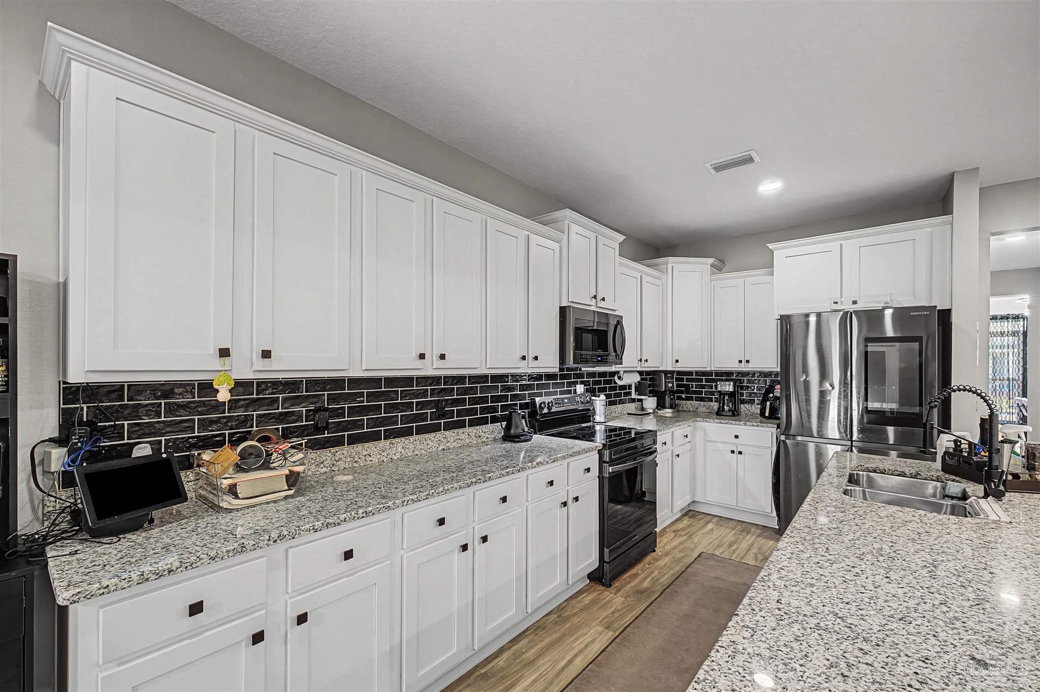 327 Cayden Way Cantonment, FL 32533 - Photo 5 of 64 a kitchen with stainless steel appliances granite countertop a sink stove refrigerator and white cabinets